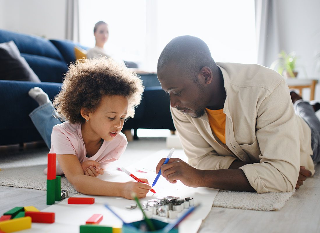 Personal Insurance - Father With Small Daughter Drawing Pictures While Laying on the Floor of Family Living Room